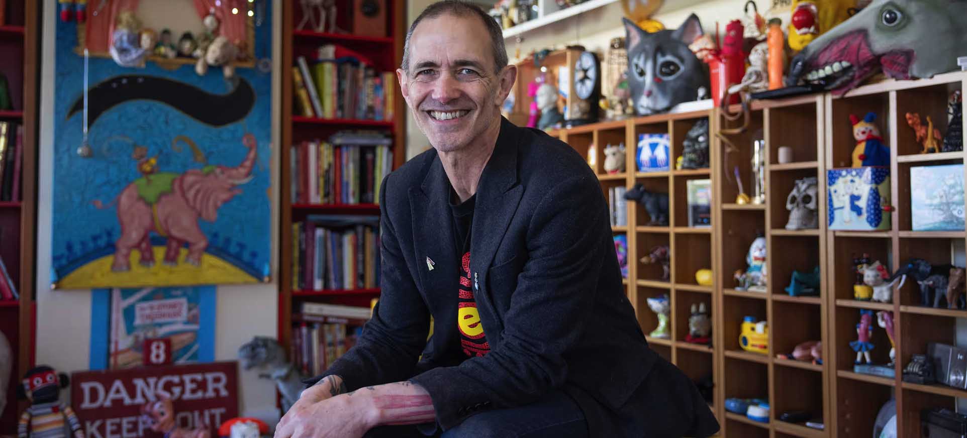 Andy Griffiths looking at the camera smiling surrounded by books